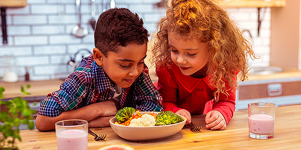 duas crianças olhando o prato de comida 